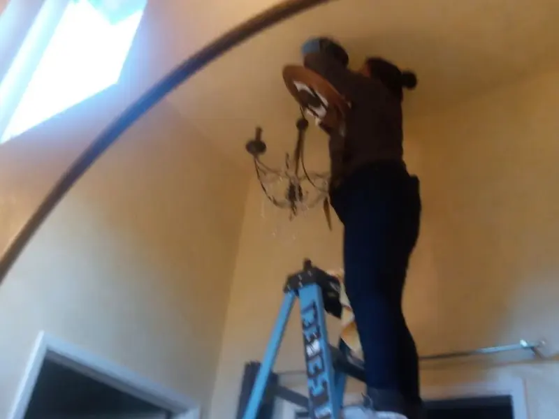 Electrician installing a chandelier in a Silver Hill residence